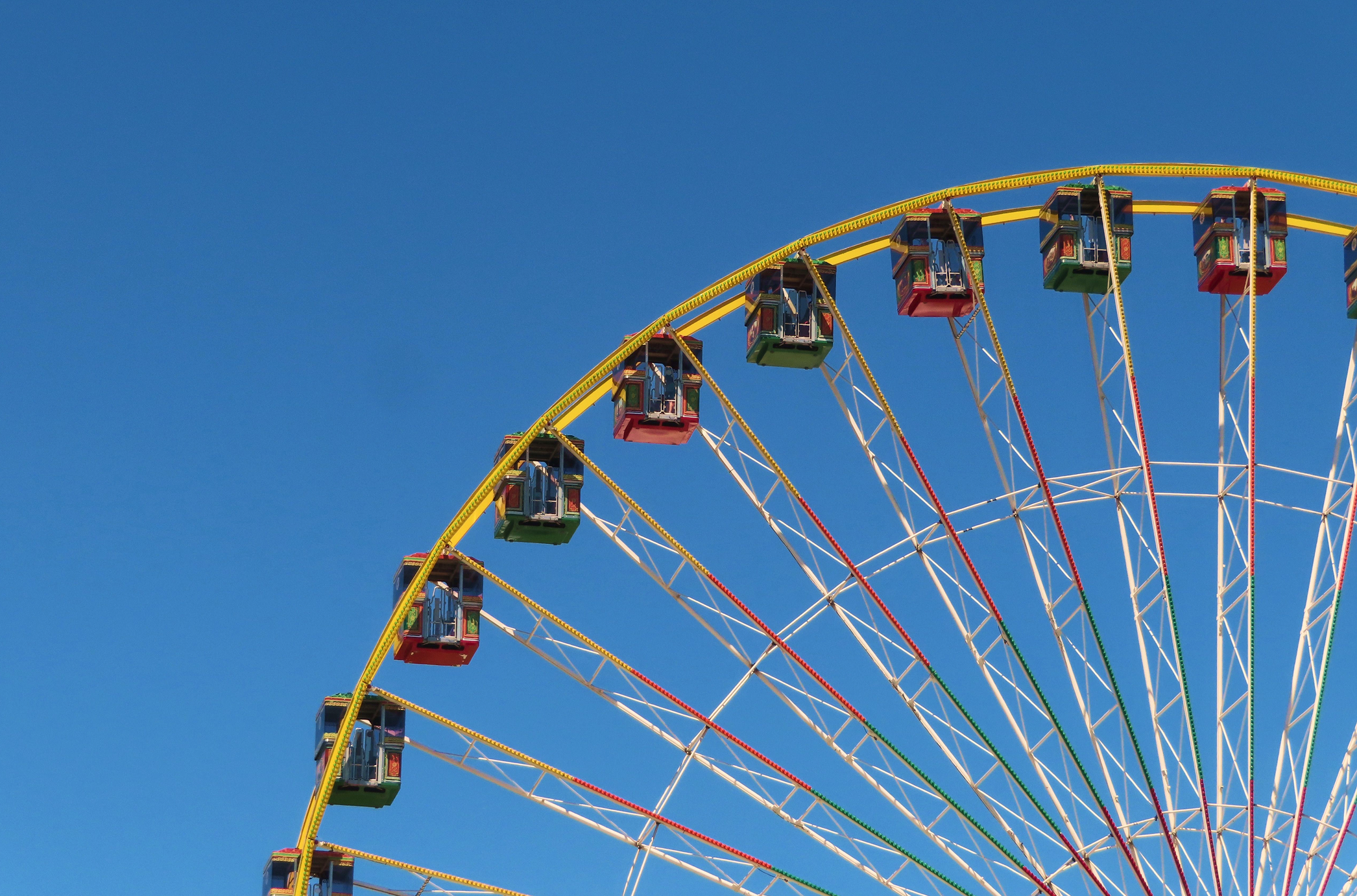 Colorful Ferris wheel cabins against a clear blue sky.